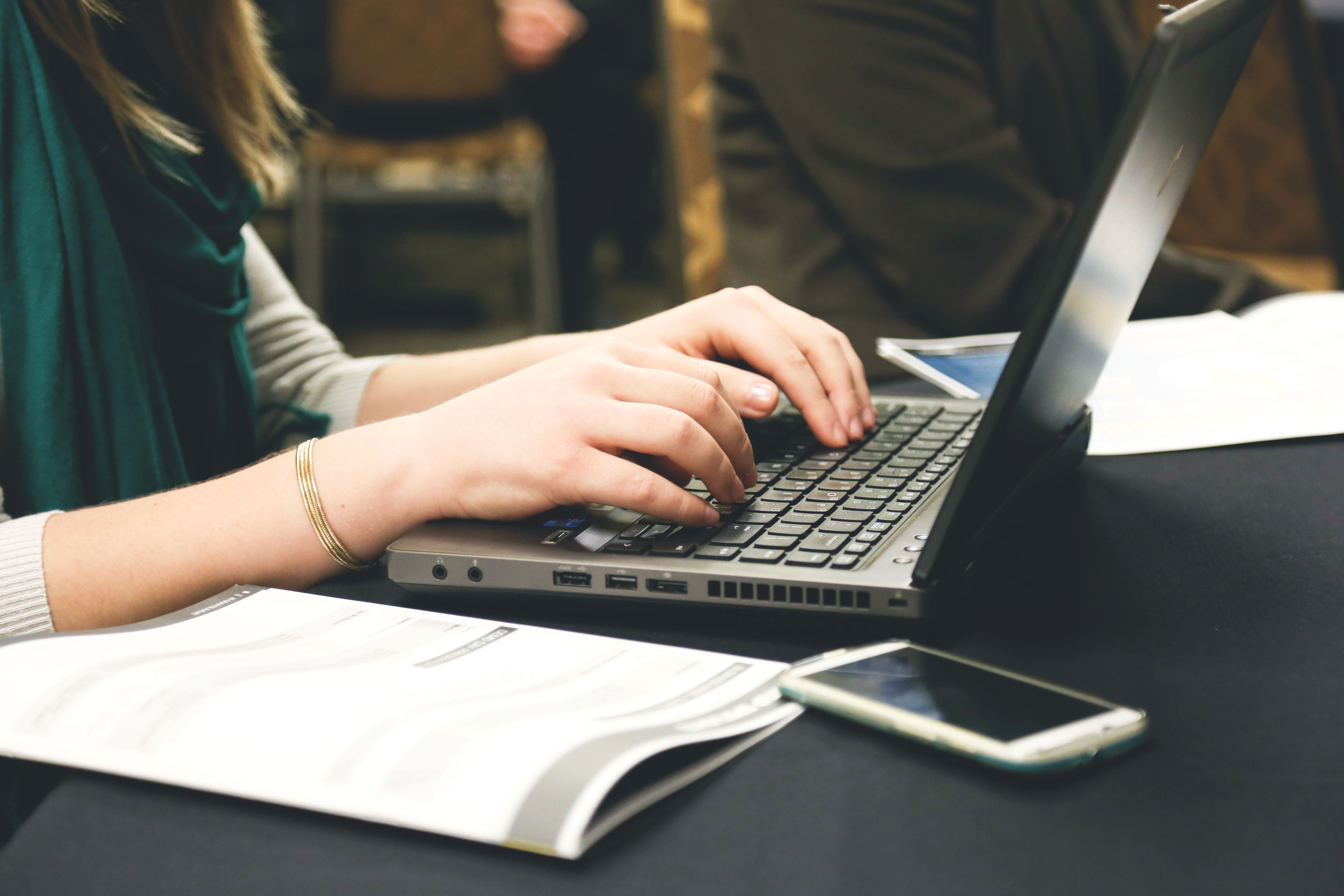Creator typing a social media caption on a laptop, comparing the Canva AI caption generator with other tools