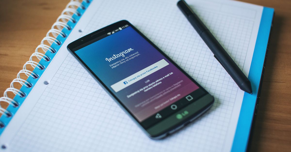 Smartphone displaying the Instagram app beside a notepad and pen, planning an Instagram hashtag strategy for 2026