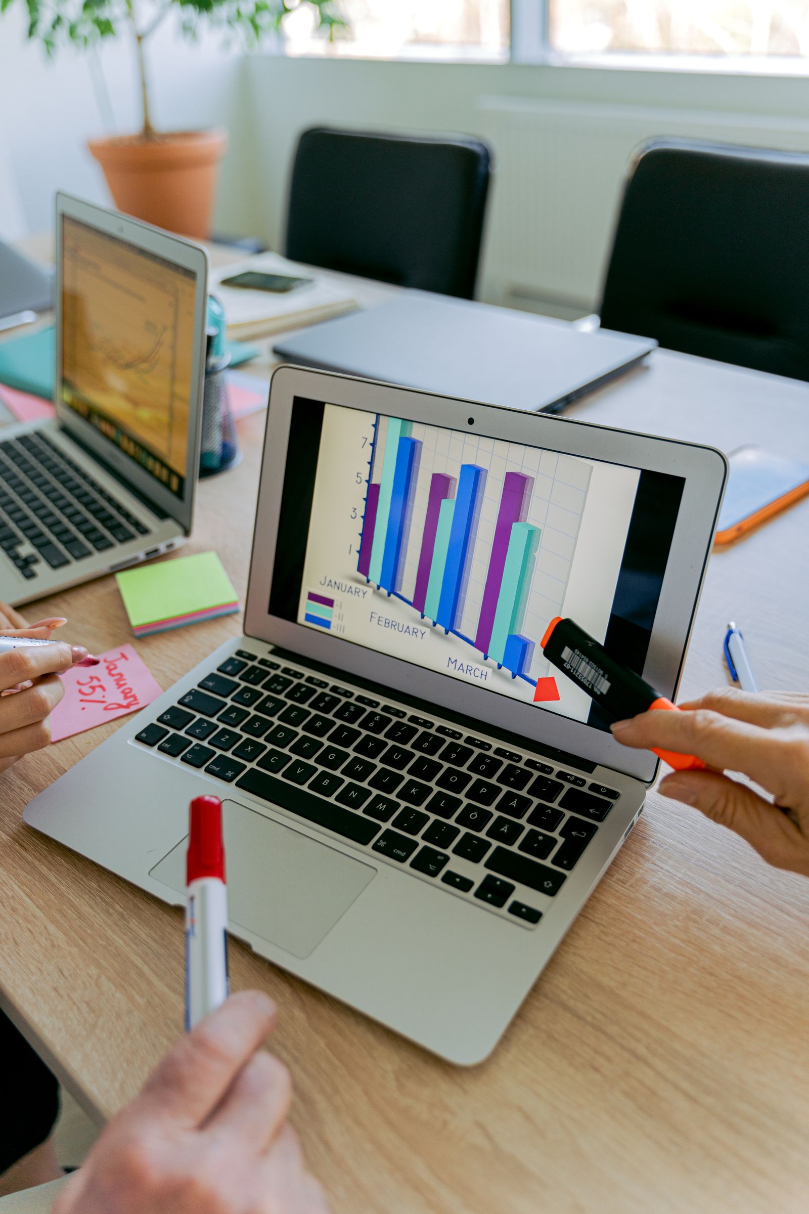 Team reviewing social media KPIs on a business graph displayed on a laptop screen
