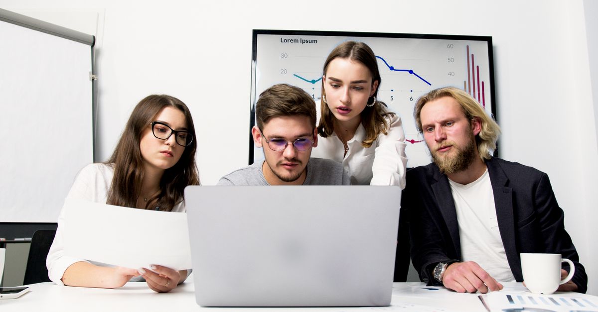Social media team managing client accounts together around a laptop in a meeting