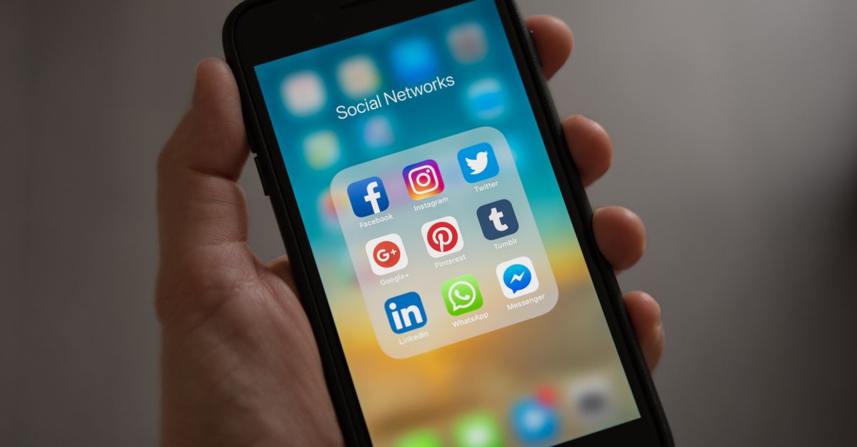 Person holding a phone showing social media apps — responding to negative comments on social media